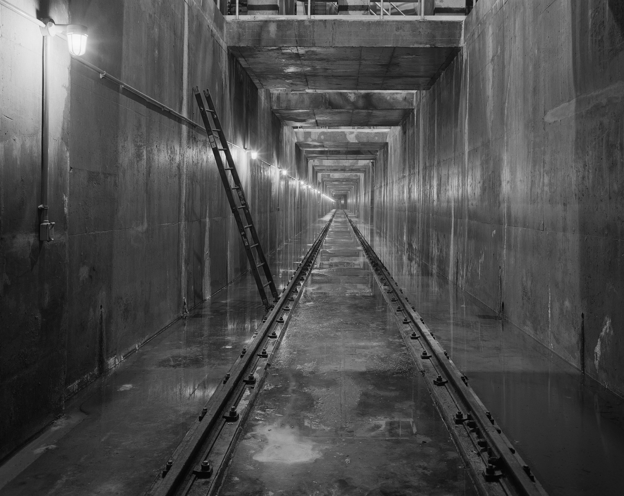 A black and white image of an underground New York City water tunnel.
