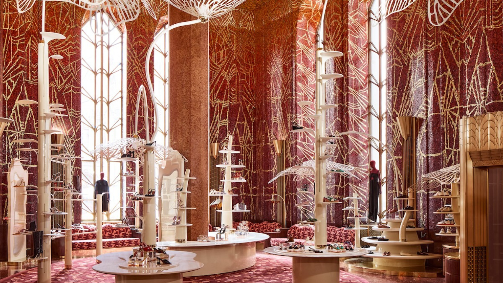 Luxurious store interior with tall art deco windows, red patterned walls, and modern white display stands.