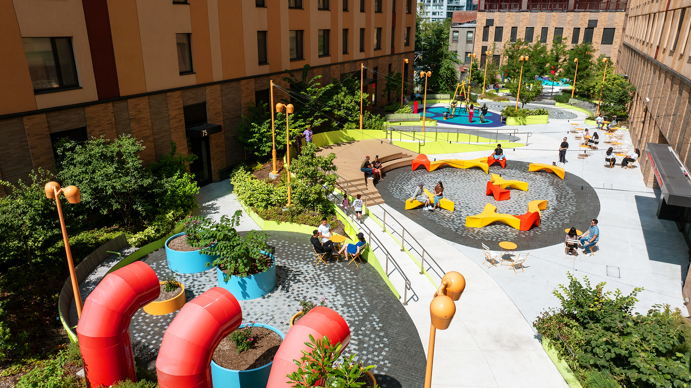 Colorful urban courtyard with seating, play areas, greenery, and people enjoying the outdoor space.